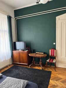 a living room with a tv and a table with a table at Lyrius Vendégház - Debrecen in Debrecen