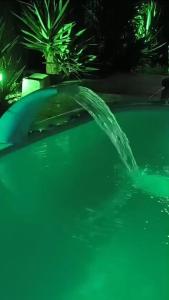 a water fountain in a swimming pool at night at Pousada da Nani in São Gabriel