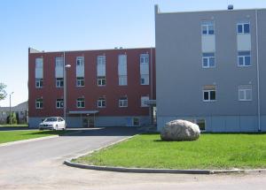 a building with a rock in the grass in front of a building at Haapsalu Kutsehariduskeskuse hostel in Haapsalu