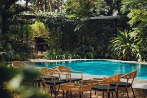 a group of chairs and a swimming pool at Botanique Goa in Assagao