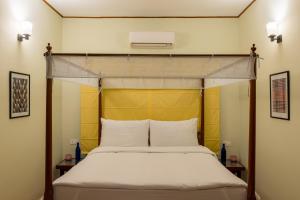 a bedroom with a bed with a yellow headboard at Botanique Goa in Assagao
