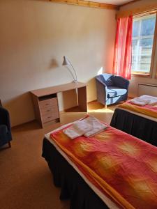 a room with two beds and a desk and a chair at Vertshuset gamlebirkeli in Drilen
