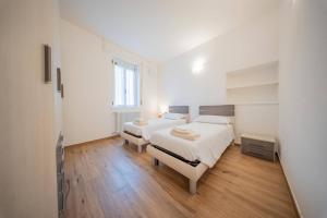 a white bedroom with two beds and a mirror at Castelaus, Lake view, 1 Min Walk from the Lake in Dervio +22 photos