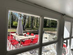 a patio with a table and red chairs and an umbrella at Gîte la plotuère in Gy-en-Sologne