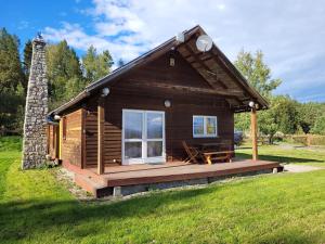 a small log cabin with a deck and a chimney at Domek na Wzgórzu in Wojcieszyce