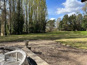 a bench in a park with a field and trees at Gîte la plotuère in Gy-en-Sologne