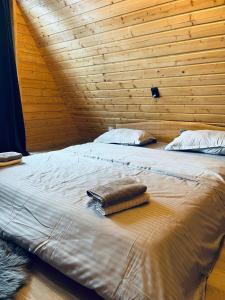 two beds in a wooden room with towels on them at Cabana Muncelus in Lupşa