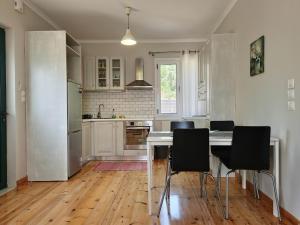 a kitchen with a table and black chairs in it at Peonia Flower House in Asprogerakata