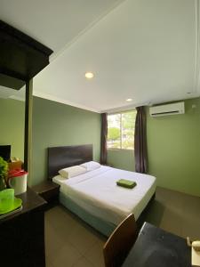 a bedroom with a bed and a table and a window at Perdana Hotel Labuan in Labuan