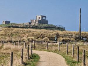 a person walking down a dirt road with a building on a hill at Evasion mer à Ostende in Ostend