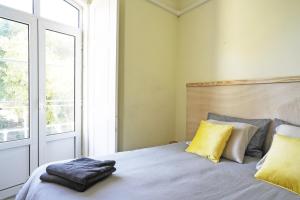 a bedroom with a bed with yellow pillows and a window at Casa Saint Yves in Setúbal +33 photos