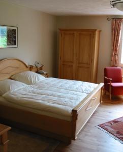 a bedroom with a large bed and a red chair at Wißkirchen Hotel & Restaurant in Odenthal