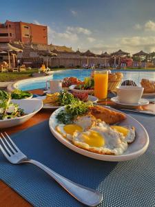 a breakfast table with eggs and toast next to a pool at Fanar Hotel in Ain Sokhna