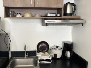 a kitchen counter top with a sink and a kitchen appliance at Urban Oasis Symphony Pool in Cebu City +23 photos