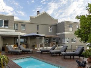 a house with a pool and chairs and an umbrella at Absolute Ocean Boutique Guesthouse in Hermanus