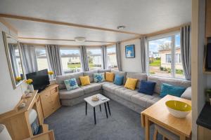 a living room with a couch and a tv at Long Beach Park Caravan, Hembsy in Great Yarmouth