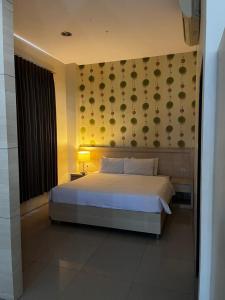 a bedroom with a large white bed and a wall at Miracle Hotel Manado in Manado