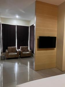 a living room with two chairs and a flat screen tv at Miracle Hotel Manado in Manado