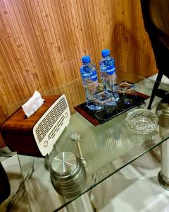 a glass table with two bottles of water and a tray of dishes at Hotel Five Rivers - 2 Min to Allama Iqbal International Airport, Lahore in Lahore