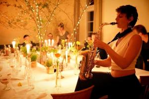 a woman playing a saxophone in front of a table at Seegut Blaue Blume in Buchenhain