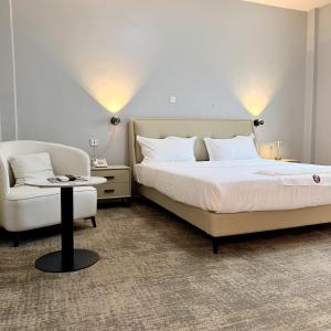 a bedroom with a bed and a chair at James Hotel & Apartments in Juba