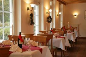 a restaurant with tables with red and white table settings at Seegut Blaue Blume in Buchenhain