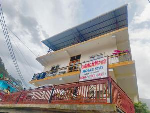 a building with a balcony with a sign on it at Ganga Kinaare Homestay in Uttarkāshi