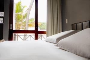 a bedroom with a bed and a window with a palm tree at Pousada Maraca Beach in Porto De Galinhas
