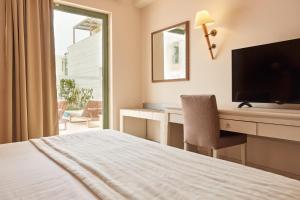 a hotel room with a bed and a desk with a television at Giannoulis - Grand Bay Beach Resort (Exclusive Adults Only) in Kolymvari