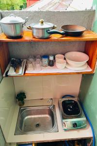 a kitchen with a sink and pots and pans on a shelf at Lazy Daze Hometel Boracay in Boracay +25 photos