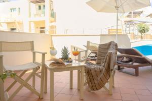 a patio with a table and chairs and an umbrella at Giannoulis - Grand Bay Beach Resort (Exclusive Adults Only) in Kolymvari