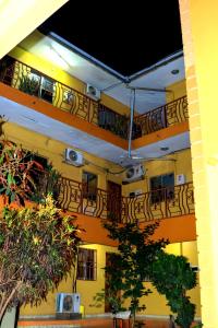 a yellow building with balconies and tables and trees at James Hotel & Apartments in Juba