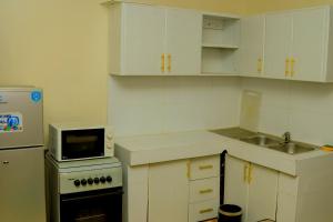 a small kitchen with white cabinets and a microwave at James Hotel & Apartments in Juba