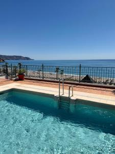 a swimming pool with the ocean in the background at Apartamentos HC Burriana Playa in Nerja