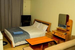a bedroom with a bed and a table and a tv at James Hotel & Apartments in Juba