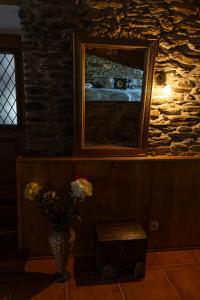 a vase with flowers in a room with a stone wall at Casa do Lagar in Vale do Porco