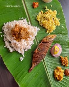 a green leaf with rice and other foods on it at Haven roots in Trivandrum