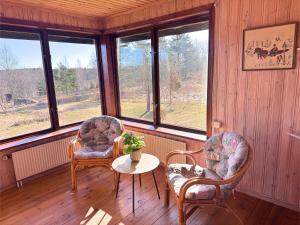 two chairs and a table in a room with windows at Hus Stora Hultet in Hultsfred