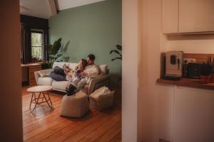 a man and woman sitting on a couch in a living room at Les Doms d'Alfred - GRINDOM in Plombières +8 photos