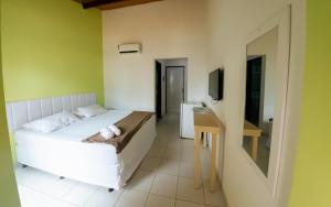 a bedroom with a white bed and a television at Pousada Maraca Beach in Porto De Galinhas