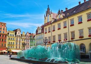 a fountain in the middle of a city with buildings at Lumina OVO in Wrocław