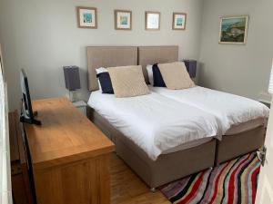 a bedroom with a bed and a desk with a television at Aigua Blava in Carbis Bay