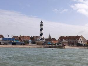 a lighthouse on the shore of a beach with buildings at maison cosy proche du port et plage in Grand-Fort-Philippe