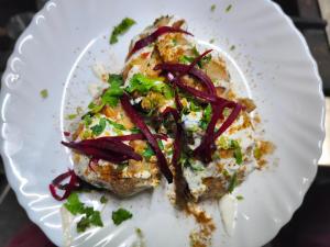 a white plate with a piece of food with red onions at Batohi hotel cafe & Restaurant in Devaprayāg +70 photos