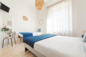 a white bedroom with two beds and a table with a chair at L'Acqua e la Pietra in Rapolano Terme