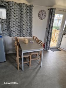 a kitchen with a table and chairs and a clock at Valras Jasmin 68 in Sérignan