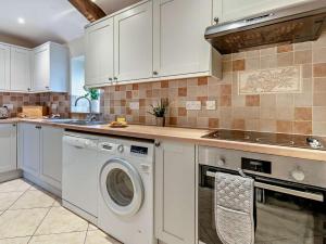 a kitchen with white cabinets and a washer and dryer at 2 Bed in Crickhowell oc-mawrw in Cwm-du +18 photos