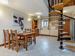 a dining room with a table and chairs and a spiral staircase at 2 Bed in Crickhowell oc-mawrw in Cwm-du