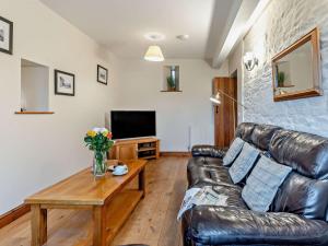a living room with a leather couch and a table at 2 Bed in Crickhowell oc-mawrw in Cwm-du