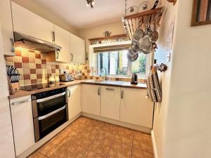 a kitchen with white cabinets and a sink and a window at 3 Bed in Aberdyfi oc-dy024 in Aberdyfi
